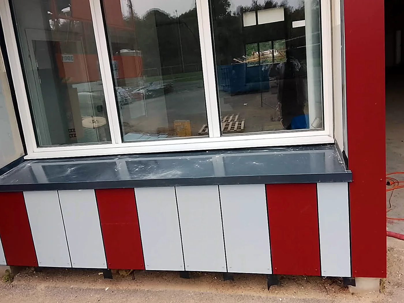 Détail du bardage bac acier rouge et gris à Étaples-sur-Mer : allège de fenêtre et panneaux de façade posés