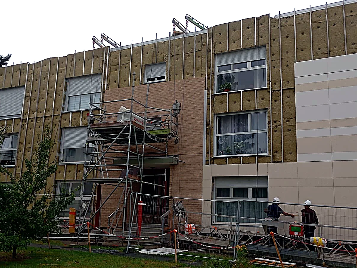 Façade d’immeuble en rénovation à Bergues : panneaux isolants posés et échafaudage devant l’entrée