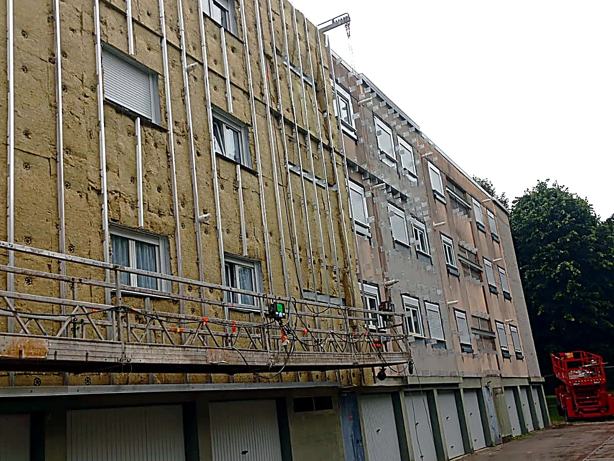 Pignon d’immeuble en cours d’isolation par l’extérieur à Bergues, avec nacelle suspendue et isolant visible