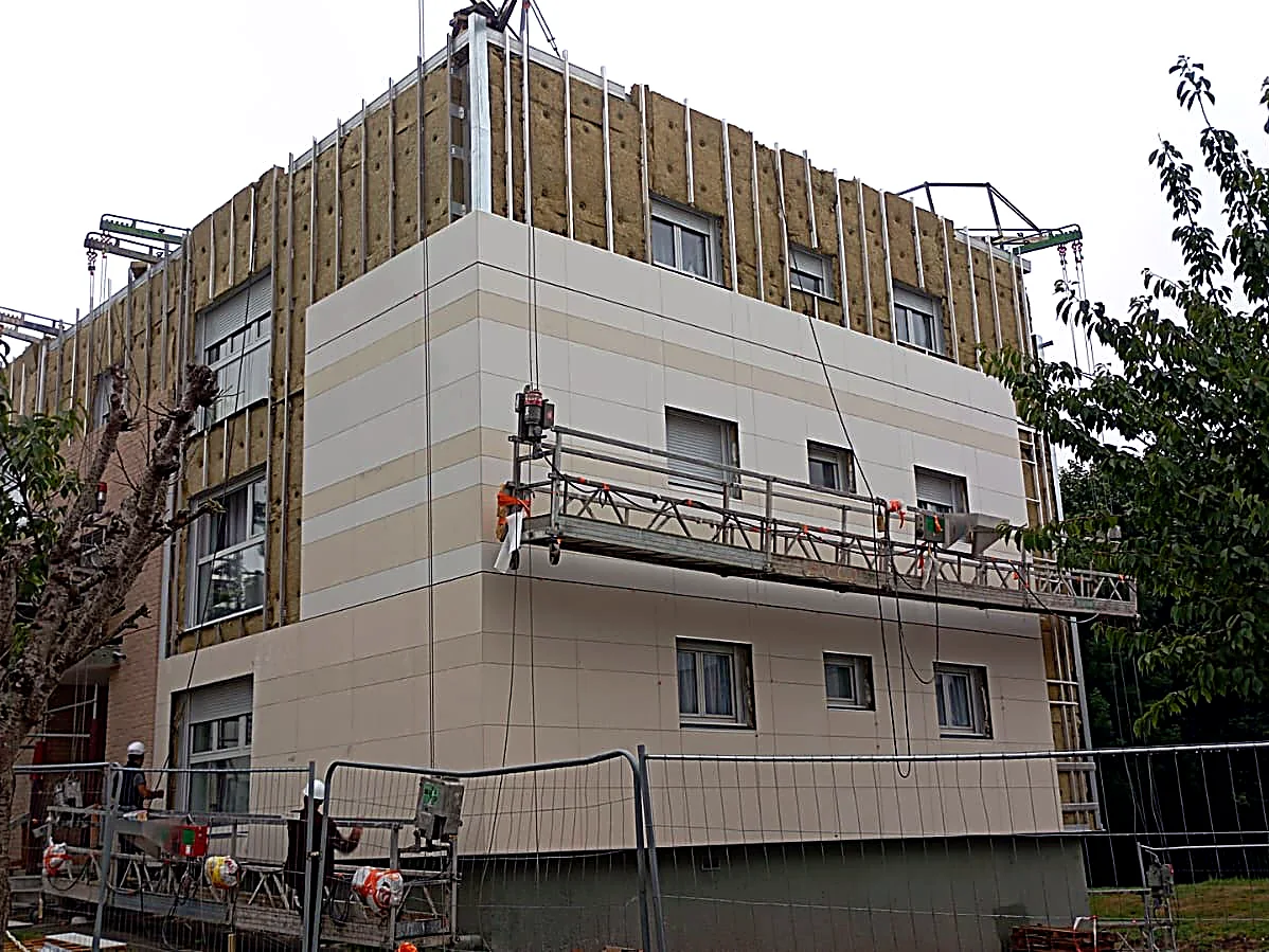 Vue d’angle du chantier de Bergues : isolant nu en partie haute et bardage beige posé en partie basse