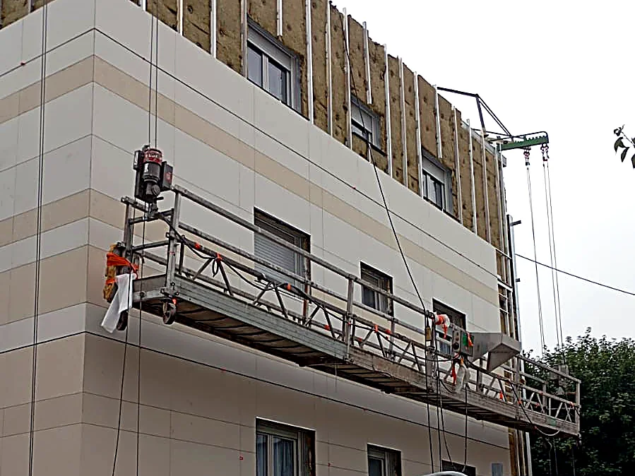 Chantier d’isolation thermique par l’extérieur à Bergues : nacelle suspendue devant la façade en cours de bardage
