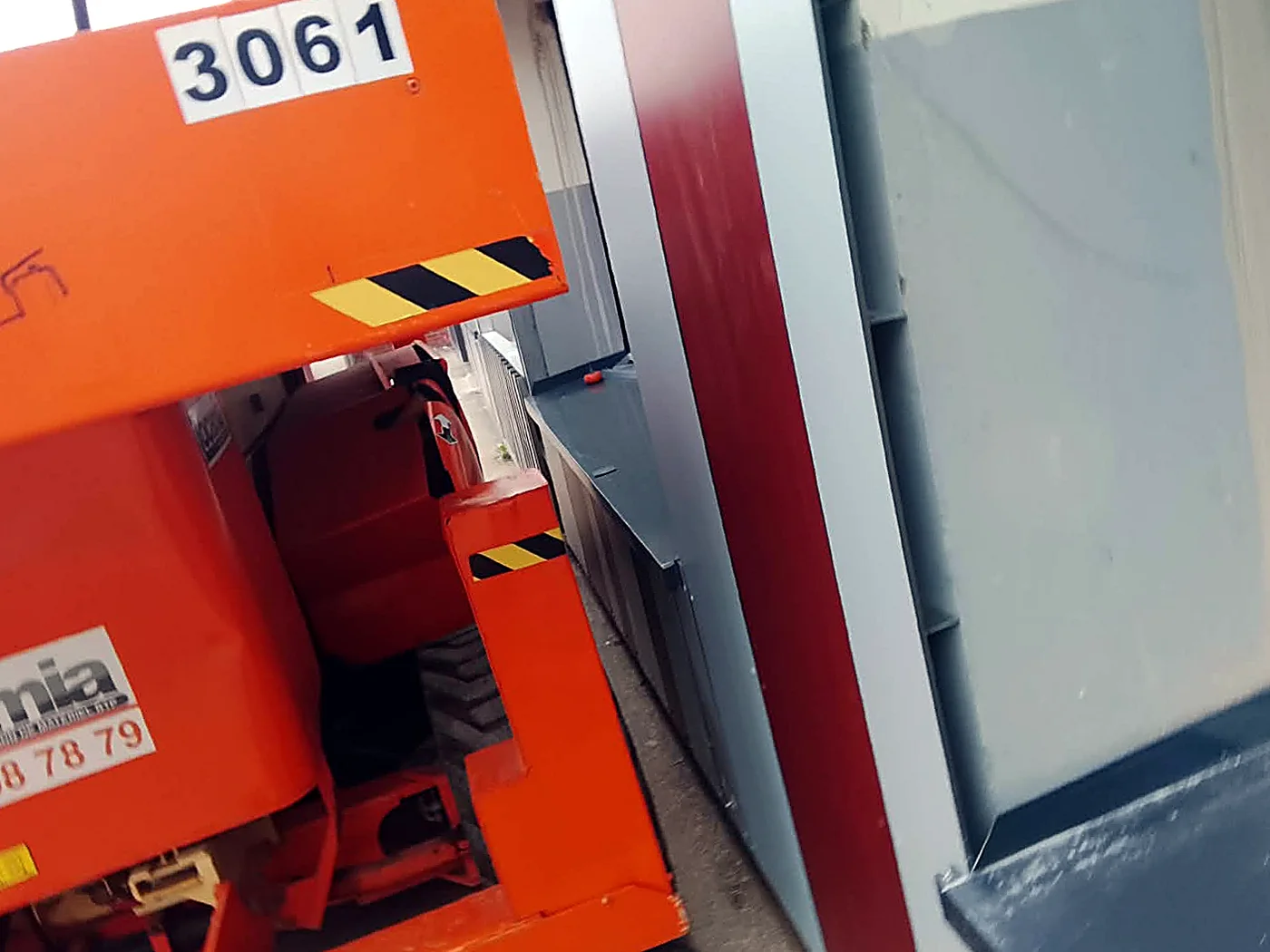 Nacelle ciseaux devant la façade en bardage bac acier rouge et gris du chantier d’Étaples-sur-Mer